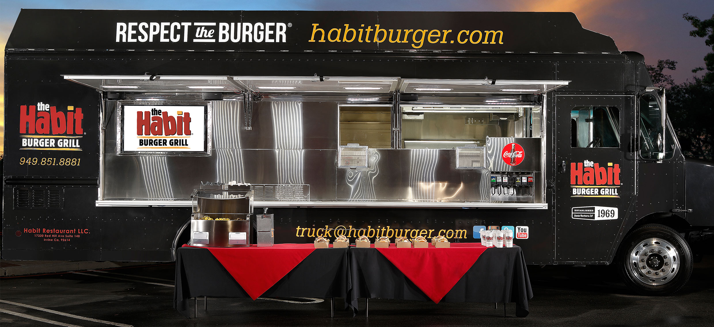 habit truck open with tables and food set up in front of it