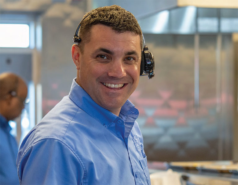 A smiling Habit Burger Grill manager with headset