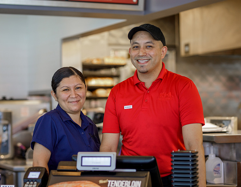 Two smiling team members by the cash register