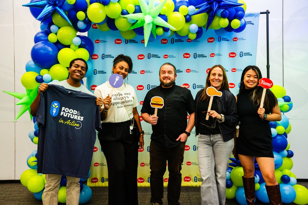 Habit volunteers posing in front of a balloon backdrop at the Blessings in a Backpack meal-packing event